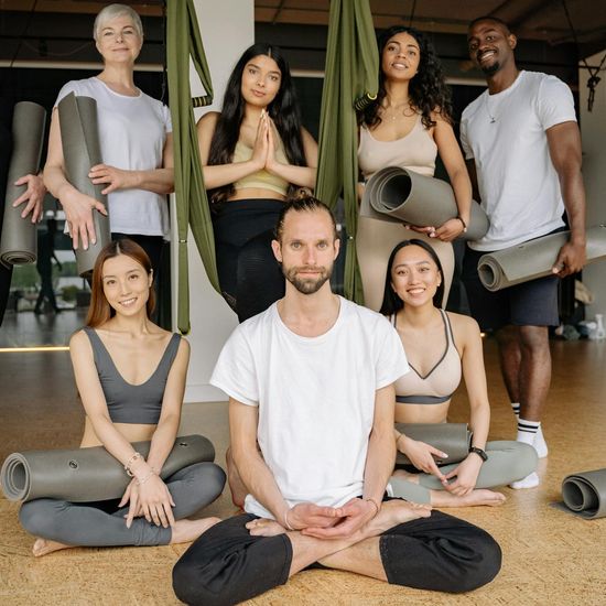 A diverse group of people preparing for a yoga class in a bright studio.