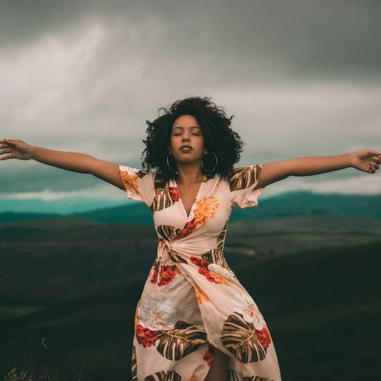 Person feeling energized and stretching outdoors against a sunset backdrop.